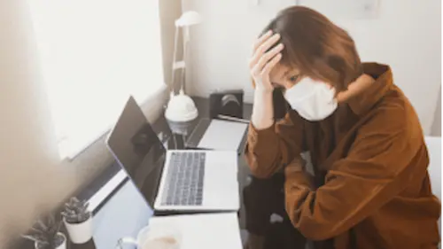 A woman holding her head while looking at a laptop