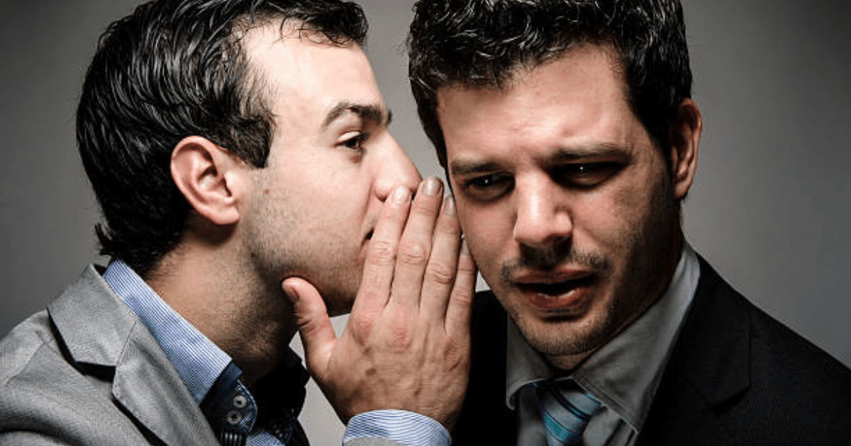 A man whispering in another man’s ear.